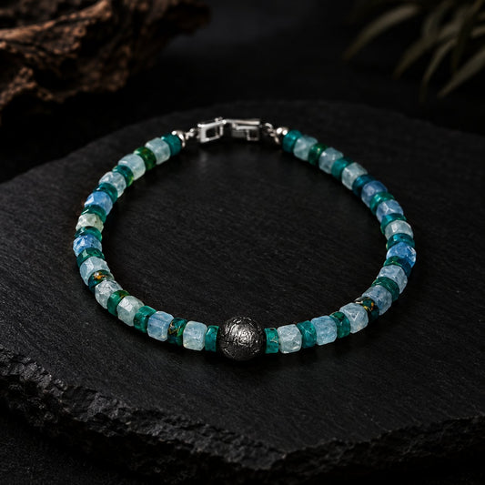 Glacial · 冰期 — glacier-blue faceted aquamarine and blue opal bracelet with an 8 mm iron meteorite center bead, photographed on dark slate