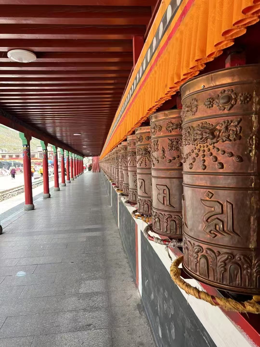Rows of copper prayer wheels in a monastery corridor on the Qinghai-Tibet Plateau
